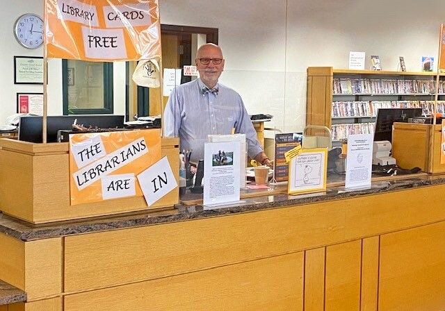 Man Standing Behind Library Counter